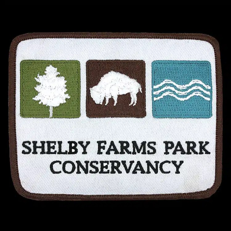 Shelby Farms Park Conservancy embroidered patch with tree, bison and water icons.